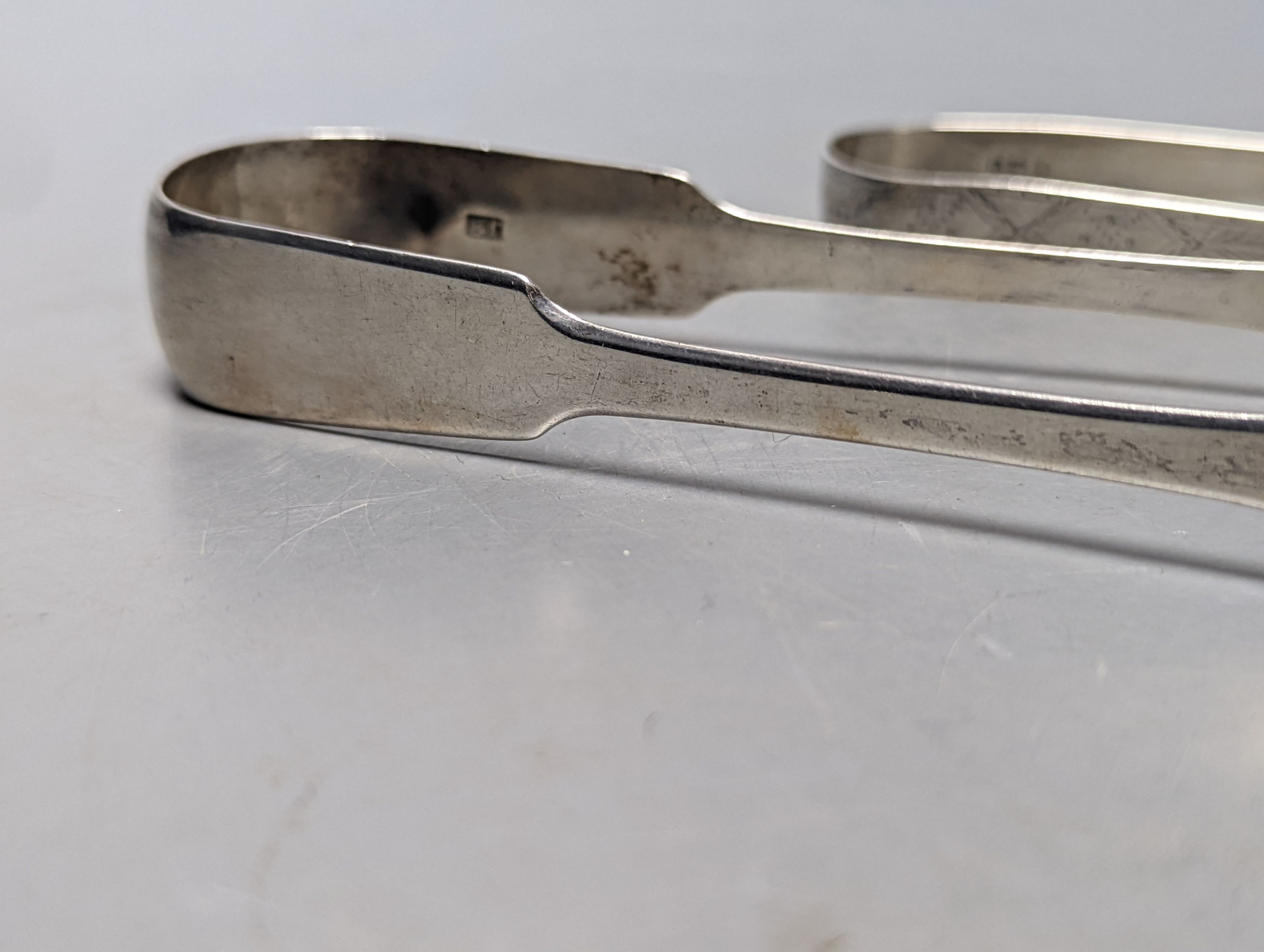 Two pairs of George III bright cut engraved silver sugar tongs and a pair of George IV silver sugar tongs, various dates and makers